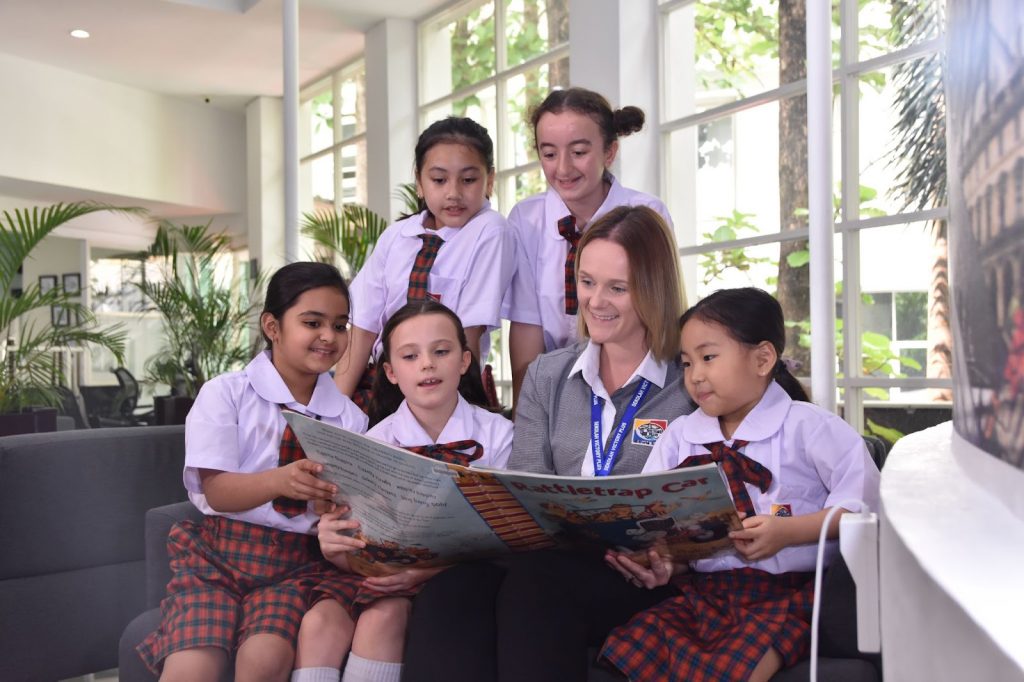 A teacher and five students of the best International Baccalaureate School in Indonesia - Sekolah Victory Plus are reading a book inside a library